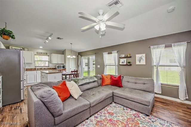 living room with ceiling fan with notable chandelier and wood-type flooring