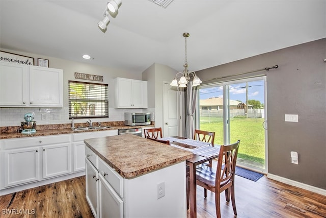 kitchen featuring a healthy amount of sunlight, a kitchen island, pendant lighting, and appliances with stainless steel finishes