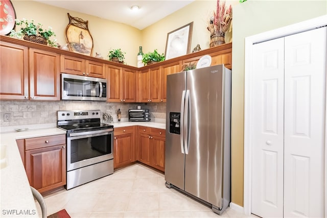 kitchen with appliances with stainless steel finishes, light tile patterned floors, and decorative backsplash