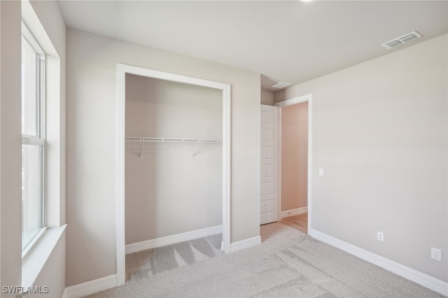 unfurnished bedroom featuring light colored carpet and a closet