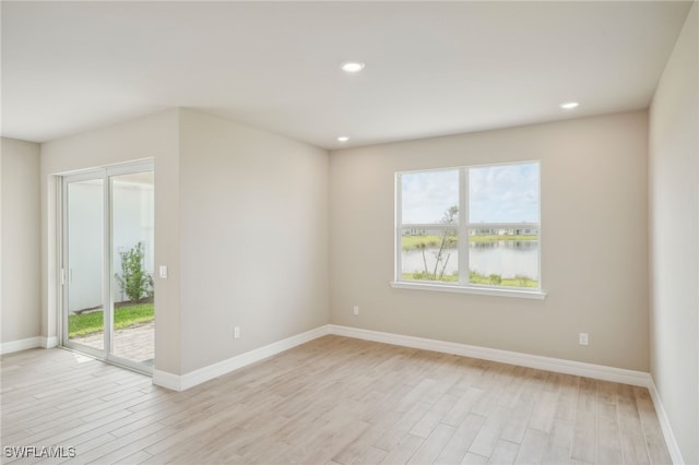 spare room with light wood-type flooring and a water view