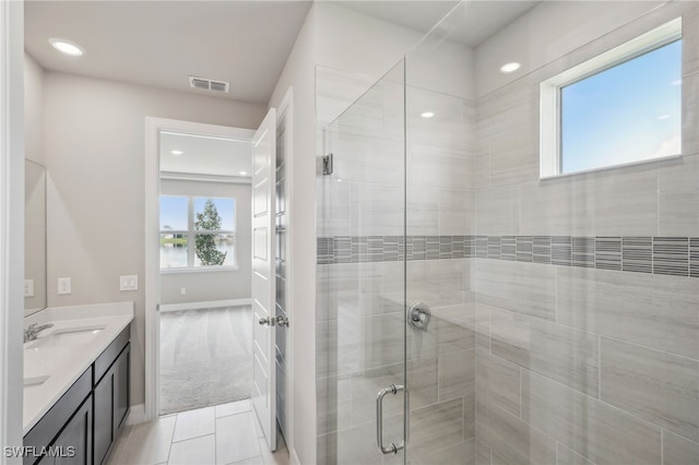 bathroom with walk in shower, a water view, vanity, and tile patterned flooring