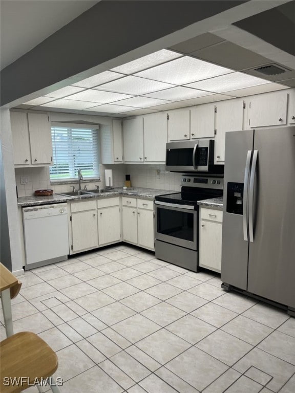 kitchen featuring white cabinetry, backsplash, light tile patterned floors, stainless steel appliances, and sink