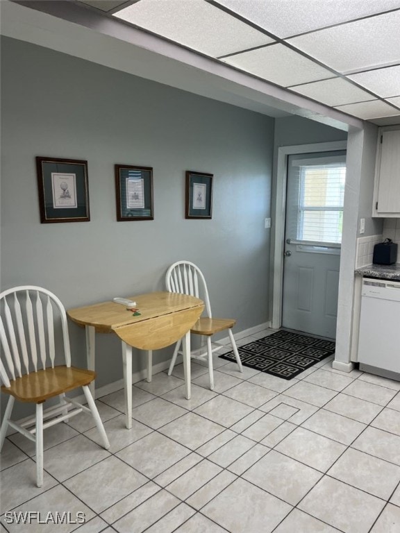 unfurnished dining area featuring light tile patterned flooring and a drop ceiling