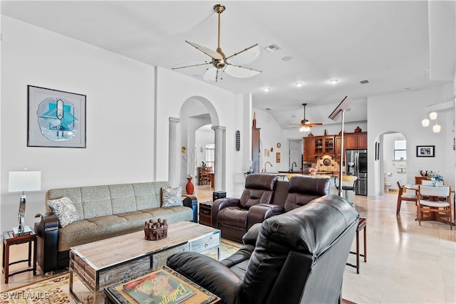 living area featuring arched walkways, visible vents, and ceiling fan