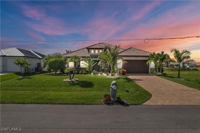 mediterranean / spanish home with a front yard, decorative driveway, an attached garage, and stucco siding