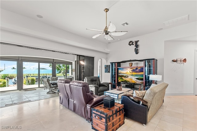 living room featuring light tile patterned floors, visible vents, arched walkways, and a ceiling fan