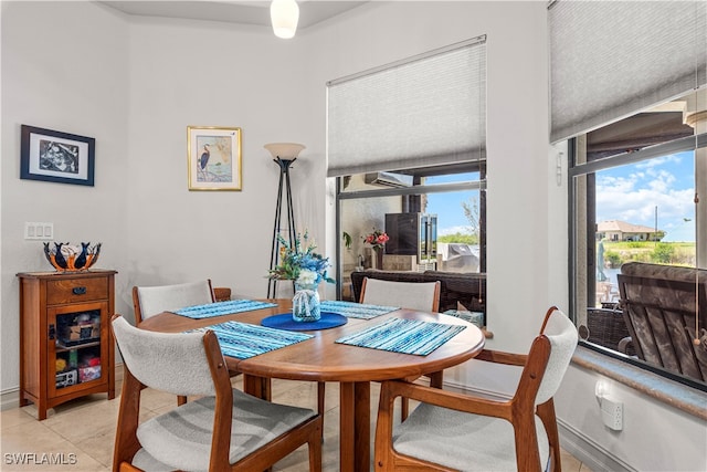 dining room featuring a healthy amount of sunlight, light tile patterned floors, and baseboards