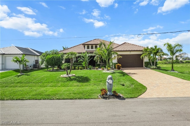 mediterranean / spanish home with a garage, a tile roof, decorative driveway, stucco siding, and a front yard