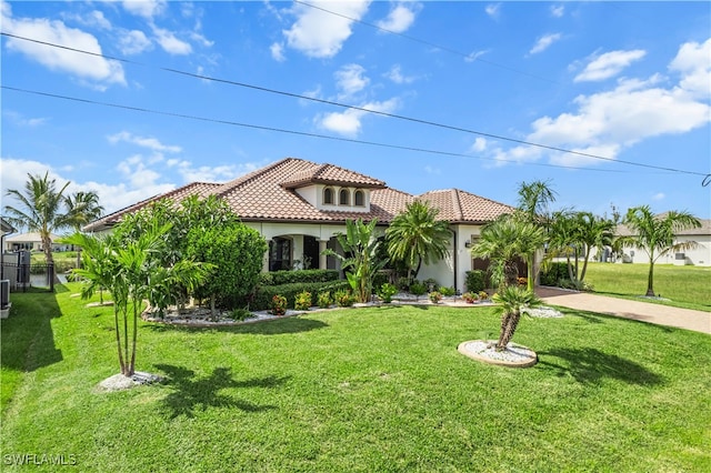 mediterranean / spanish-style house featuring decorative driveway, a tile roof, a front lawn, and stucco siding