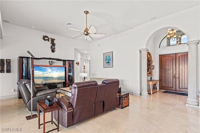 living room featuring arched walkways, ornate columns, visible vents, baseboards, and ceiling fan with notable chandelier