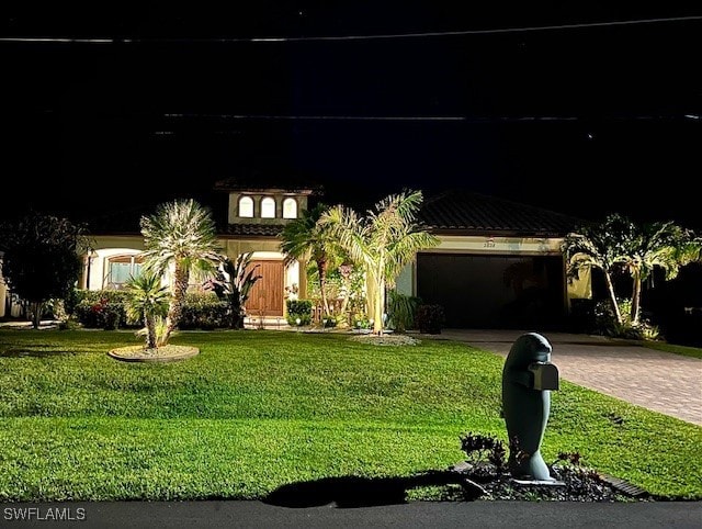 mediterranean / spanish home featuring decorative driveway and a front lawn