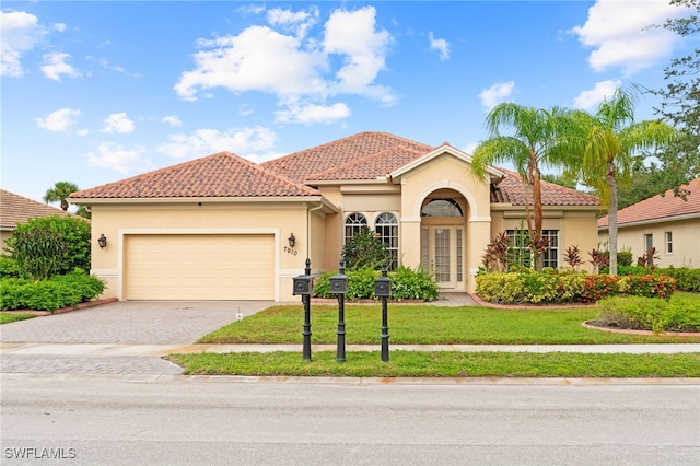 mediterranean / spanish house with a garage and a front lawn