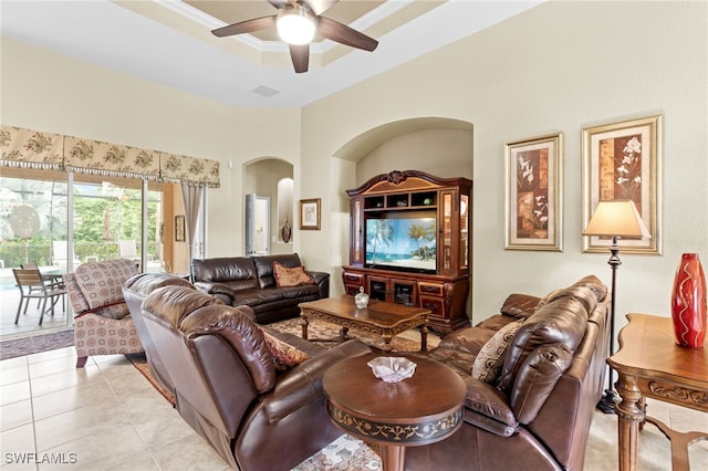 living room featuring a raised ceiling, ornamental molding, light tile patterned floors, and ceiling fan