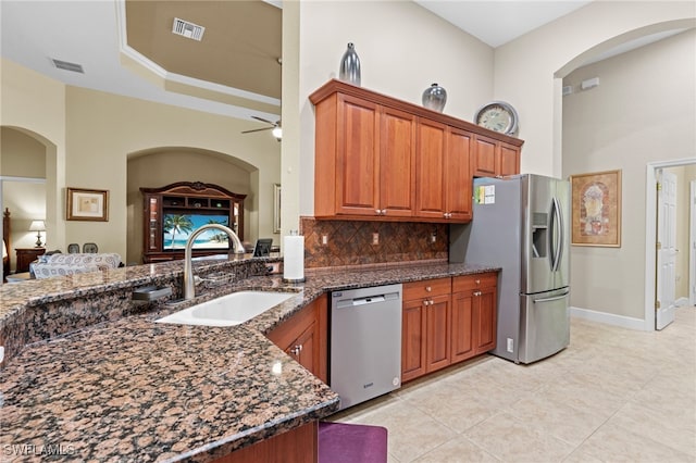 kitchen with sink, appliances with stainless steel finishes, tasteful backsplash, ceiling fan, and dark stone countertops