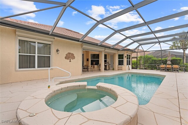 view of swimming pool featuring glass enclosure, a patio, and an in ground hot tub