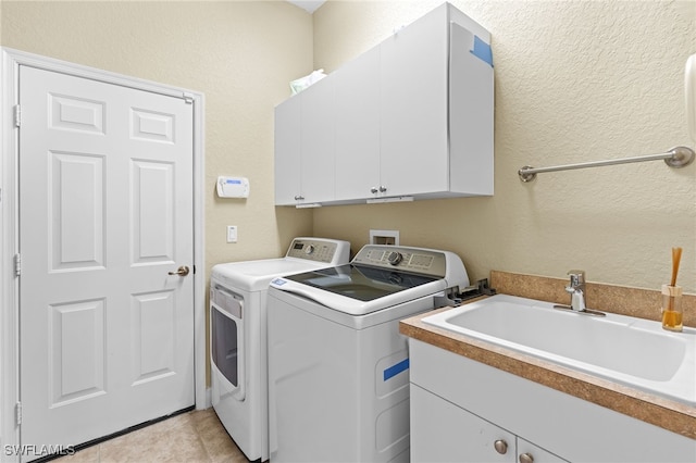 clothes washing area with cabinets, light tile patterned floors, sink, and independent washer and dryer