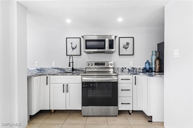 kitchen with white cabinets, light stone counters, appliances with stainless steel finishes, and light tile patterned flooring