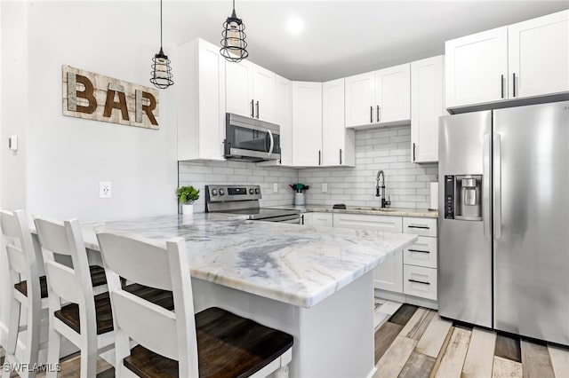 kitchen featuring a breakfast bar, white cabinets, kitchen peninsula, and appliances with stainless steel finishes