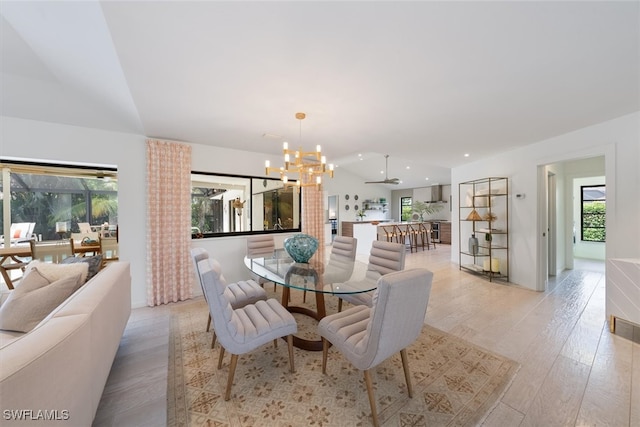 dining space with light wood-type flooring, ceiling fan with notable chandelier, and a wealth of natural light