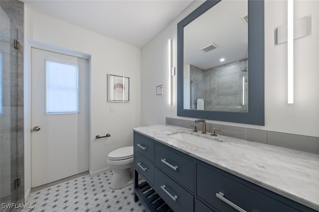 bathroom with a shower with door, vanity, and toilet