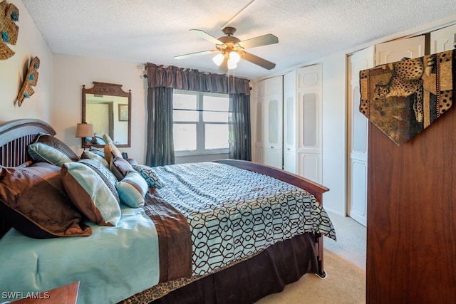 carpeted bedroom featuring ceiling fan, a textured ceiling, and two closets