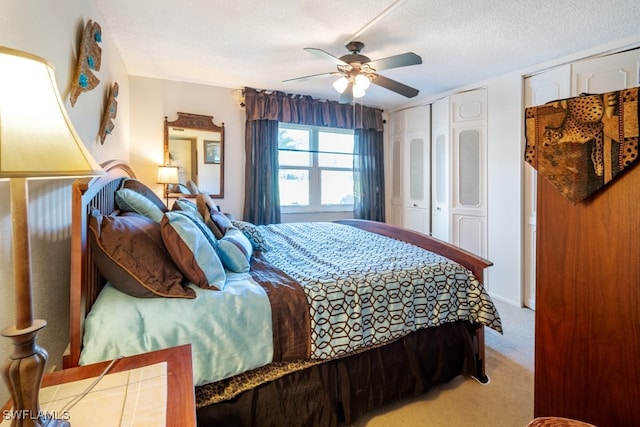 bedroom featuring a textured ceiling, ceiling fan, and light colored carpet