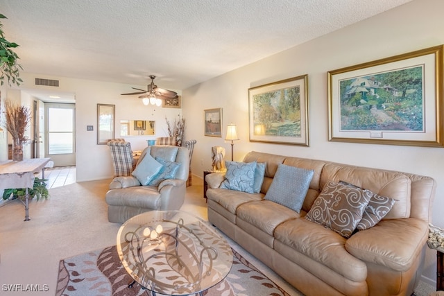 carpeted living room featuring ceiling fan and a textured ceiling