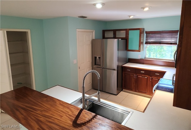 kitchen with light tile patterned floors, stainless steel refrigerator with ice dispenser, sink, and range