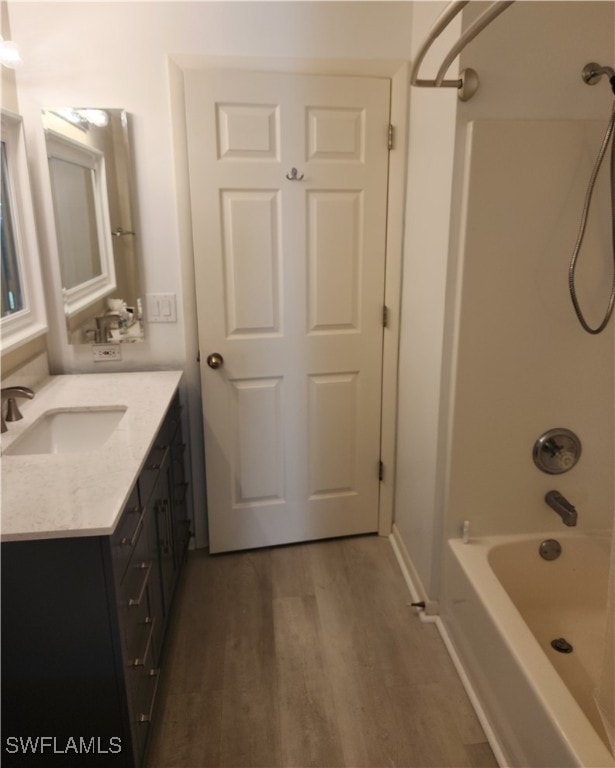 bathroom with hardwood / wood-style floors, shower / washtub combination, and vanity