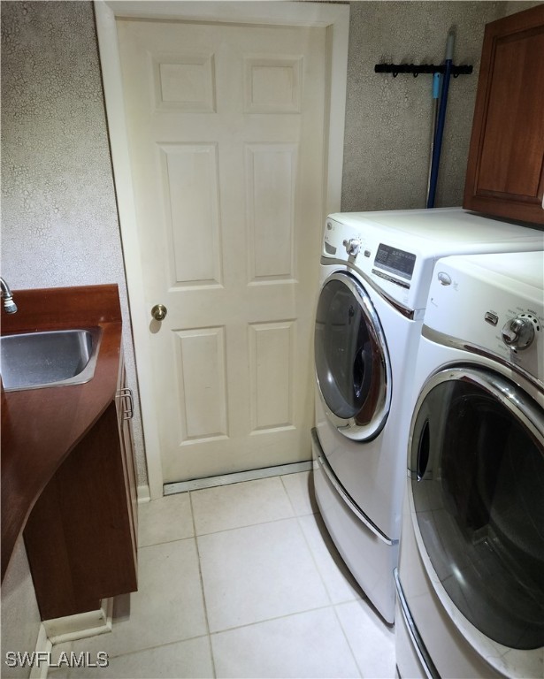 laundry area featuring light tile patterned flooring, washer and dryer, sink, and cabinets