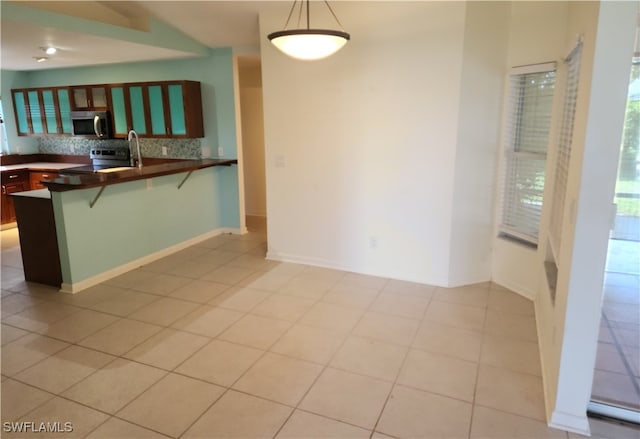 kitchen featuring hanging light fixtures, kitchen peninsula, backsplash, appliances with stainless steel finishes, and a kitchen bar