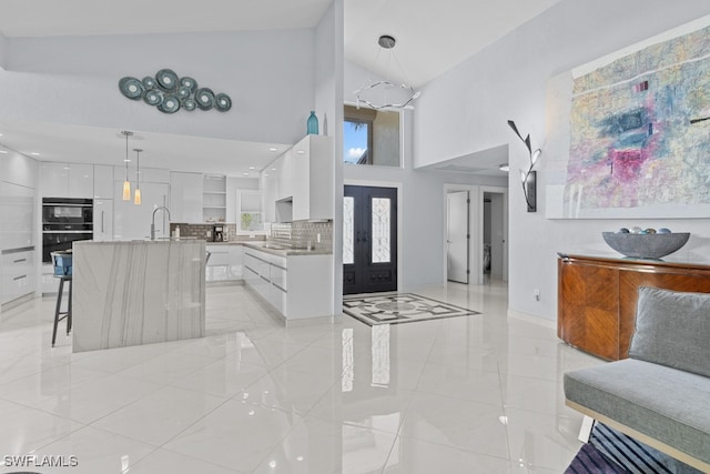 tiled entryway with high vaulted ceiling, french doors, and sink