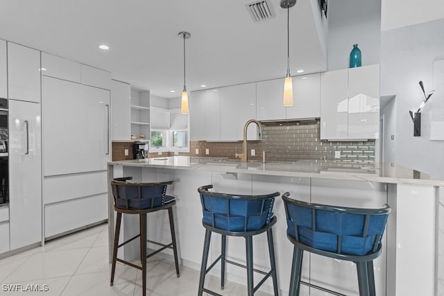 kitchen with tasteful backsplash, light tile patterned flooring, a breakfast bar area, and white cabinets