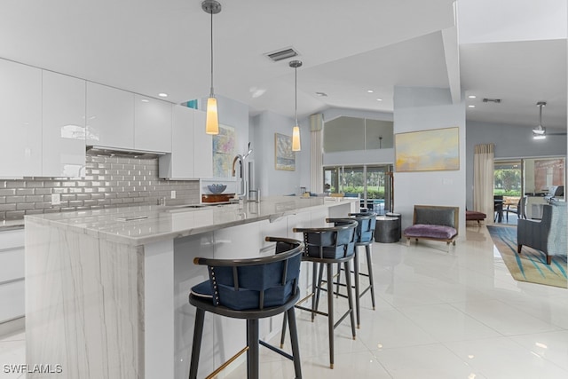 kitchen with white cabinetry, vaulted ceiling, and a healthy amount of sunlight