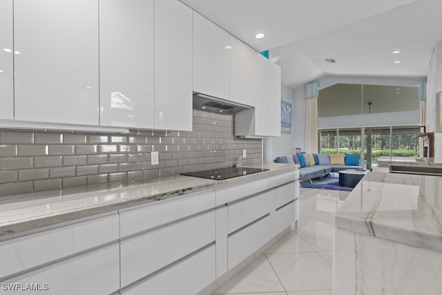 kitchen with light stone counters, black electric cooktop, backsplash, and white cabinetry