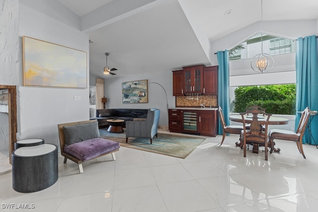 living room with ceiling fan with notable chandelier, lofted ceiling, beverage cooler, and light tile patterned floors