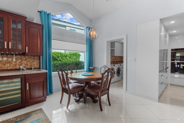 tiled dining space featuring indoor wet bar, beverage cooler, washer and dryer, and high vaulted ceiling