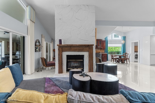 tiled living room with lofted ceiling, washer / clothes dryer, and a large fireplace