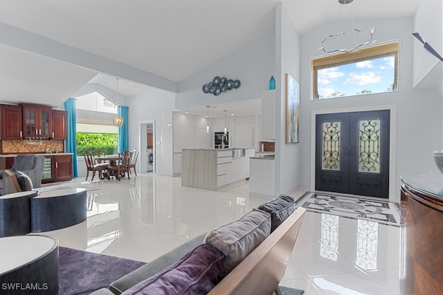 tiled entryway featuring french doors, an inviting chandelier, and high vaulted ceiling