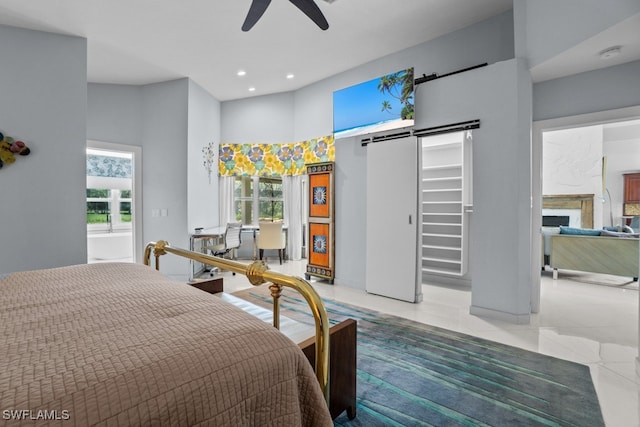 bedroom with ceiling fan, light tile patterned floors, a barn door, and multiple windows