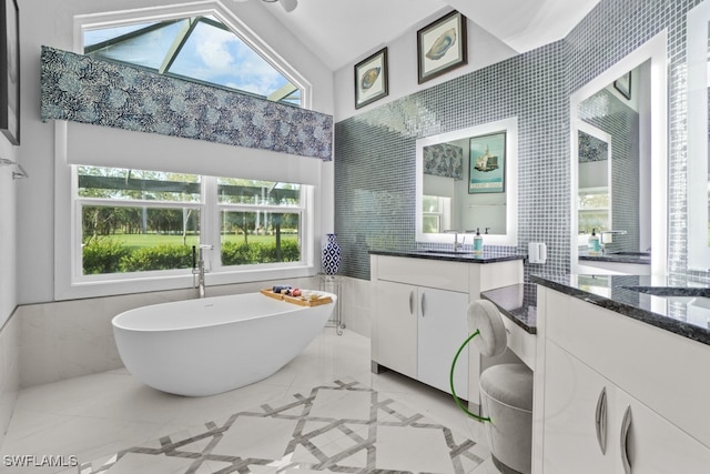 bathroom with vanity, a tub to relax in, tile walls, and lofted ceiling