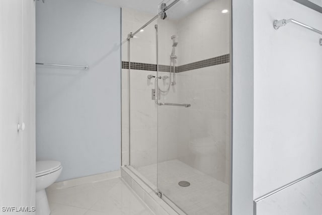 bathroom featuring a shower with door and toilet