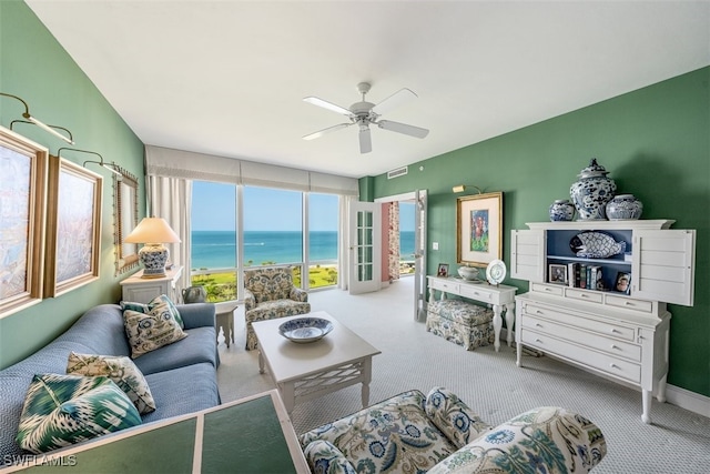 living room with ceiling fan, a water view, and light colored carpet