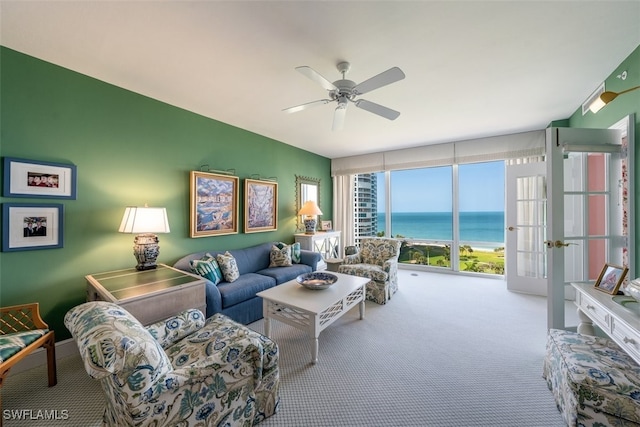 living room with ceiling fan, a water view, light carpet, and french doors