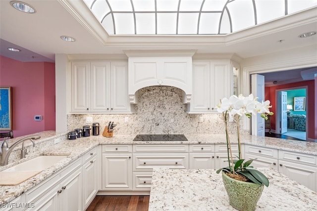 kitchen featuring black electric stovetop, white cabinets, ornamental molding, and sink