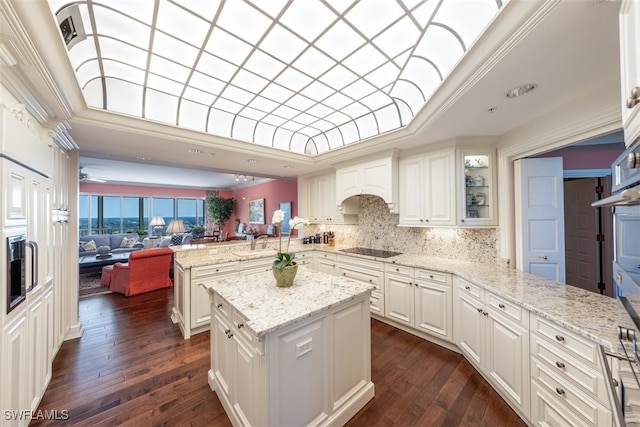 kitchen featuring white cabinets, kitchen peninsula, light stone counters, and a kitchen island