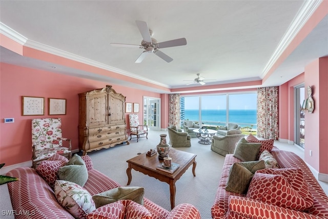 carpeted living room featuring a water view, a raised ceiling, ceiling fan, and crown molding