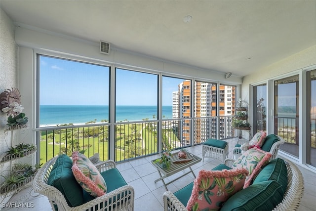 sunroom featuring a healthy amount of sunlight, a water view, and a view of the beach