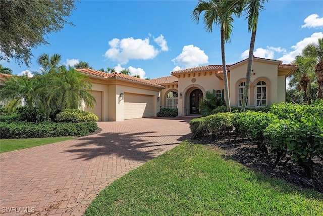 mediterranean / spanish home with a front lawn and a garage